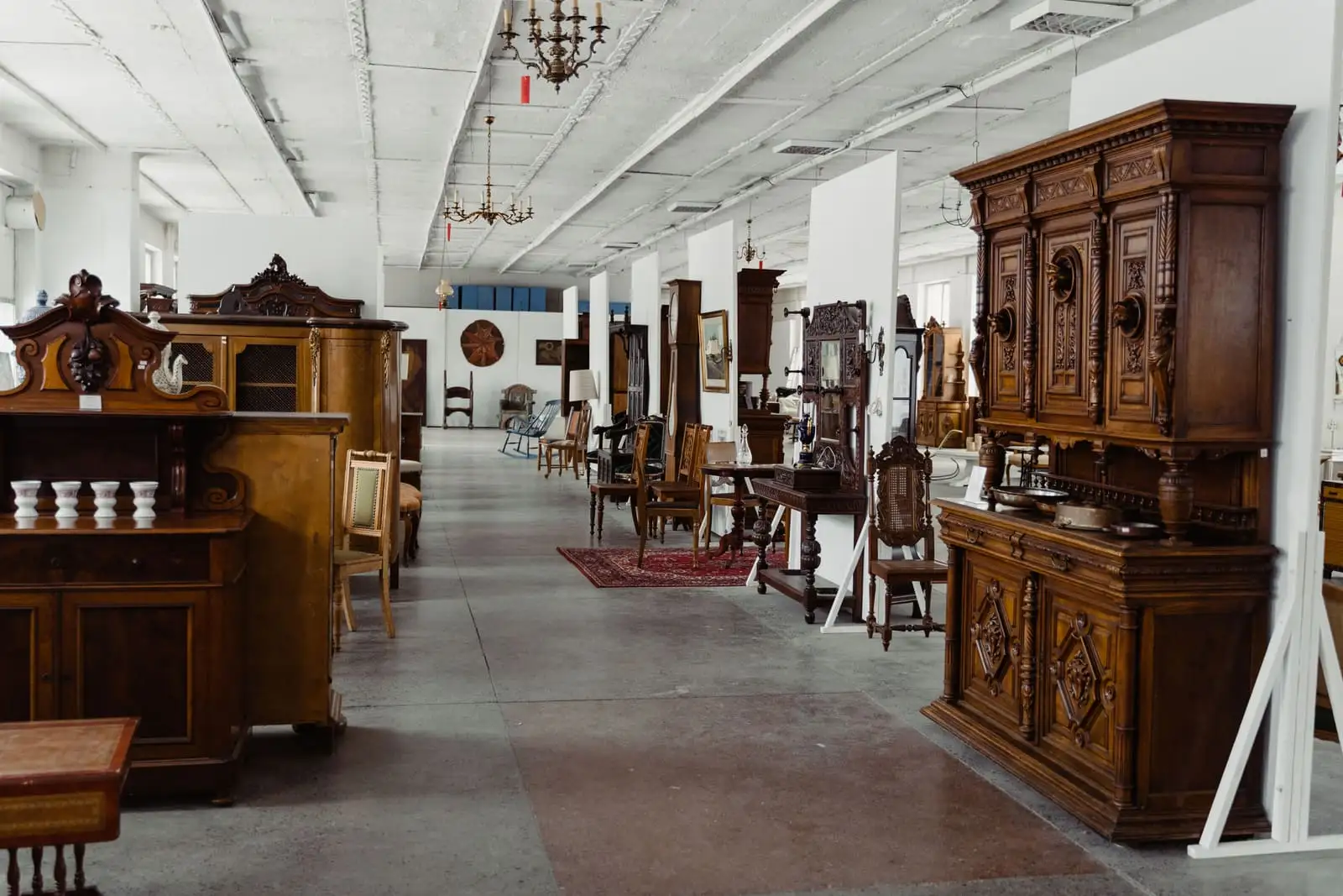 Antique wooden furniture displayed along a long showroom, the kind of estate contents a careful auction listing describes.