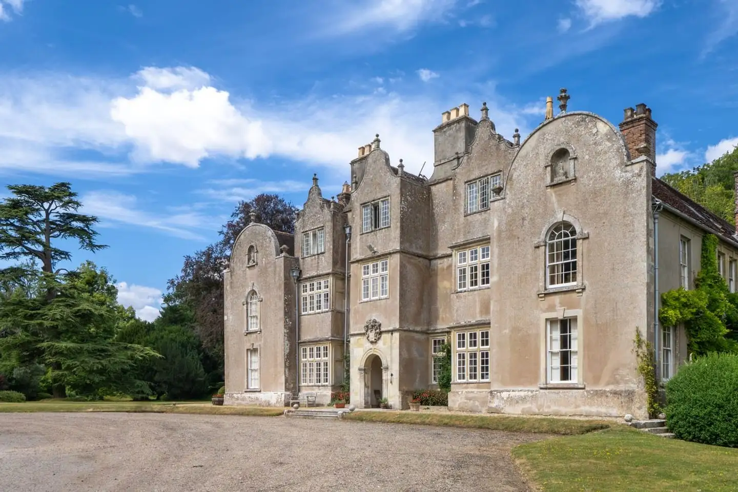 A historic manor house set in mature grounds, the kind of single-property luxury estate sale.